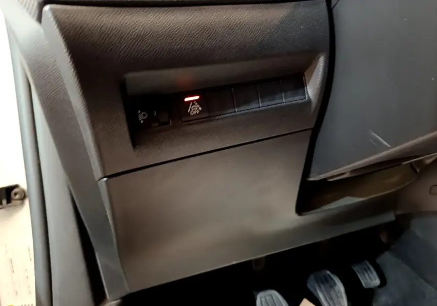 Vue intérieure sur la partie inférieure gauche du tableau de bord et pédalier du Peugeot 2008 blanc de 2021.