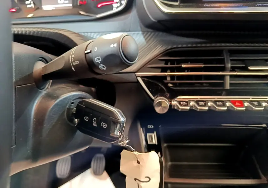 Gros plan intérieur sur le volant et la clé de contact d'une Peugeot 2008 1.5 BlueHDi, tableau de bord noir avec commandes argentées.