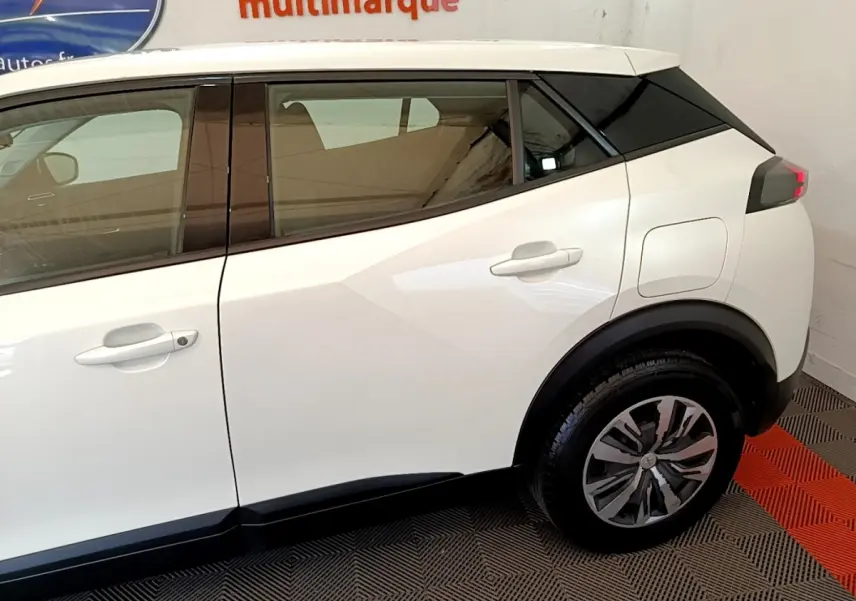 Vue latérale droite du Peugeot 2008 blanc 2021, mettant en valeur la porte arrière et la roue arrière avec jante stylisée.