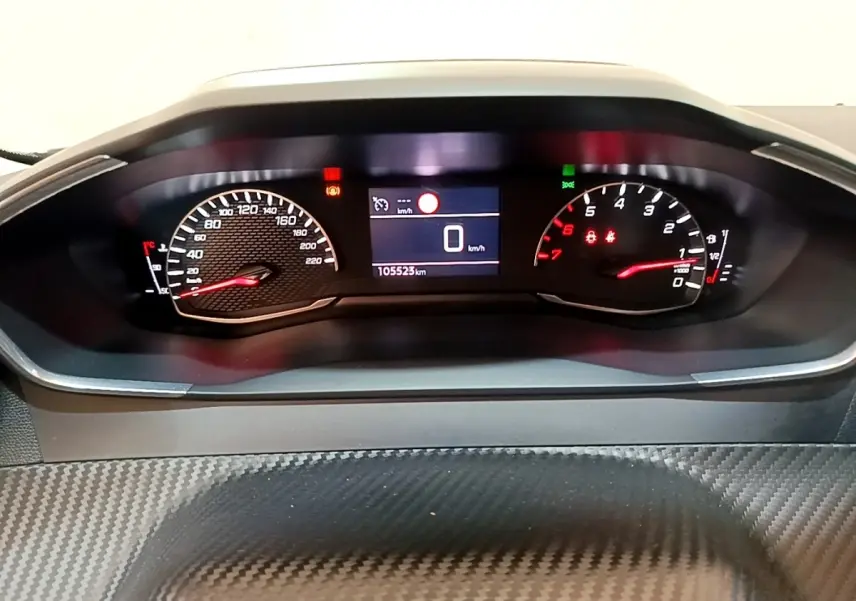 Vue rapprochée du tableau de bord numérique du Peugeot 2008 blanc, affichant 0 km/h et 105523 km au compteur.