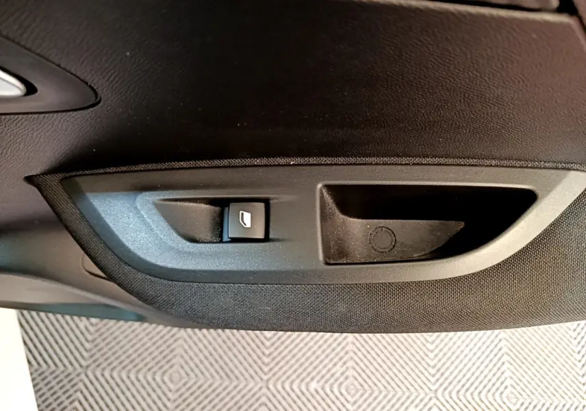 Gros plan sur le bouton de lève-vitre électrique côté porte intérieure d'une Peugeot 2008 blanche de 2021.