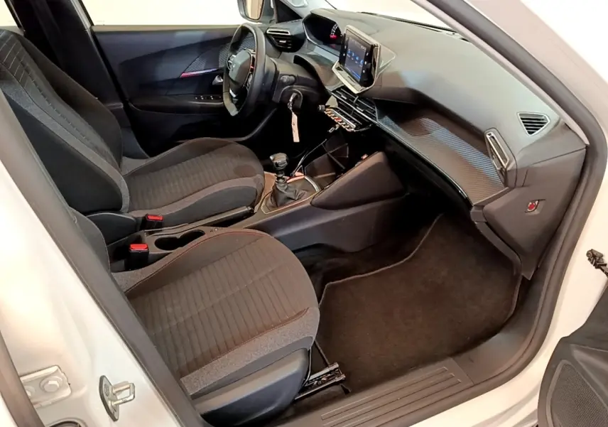 Intérieur avant droit du Peugeot 2008 blanc 2021, montrant sièges tissu, volant cuir et écran tactile central.