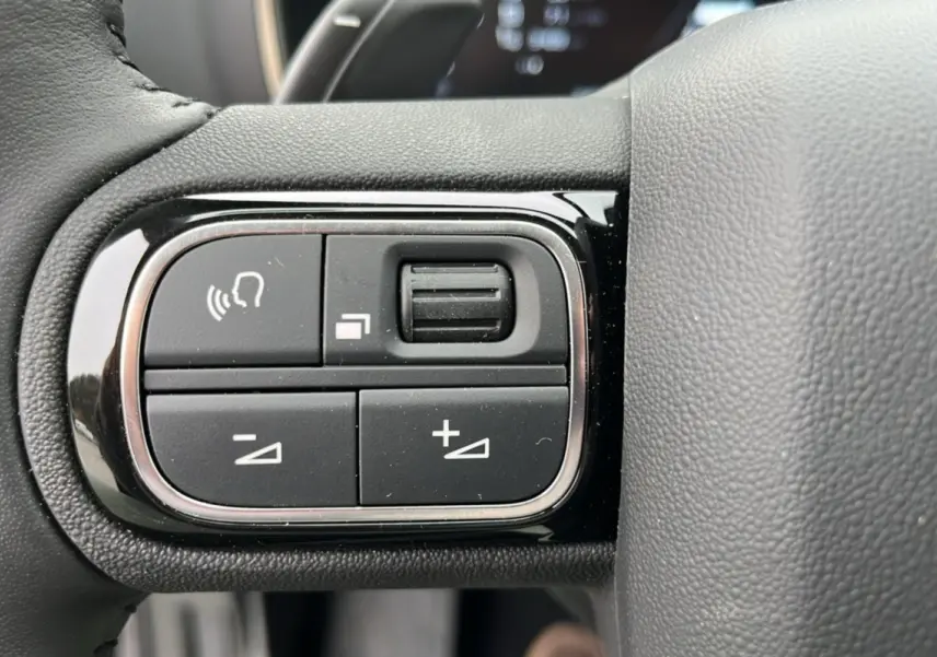 Gros plan sur les commandes multifonctions noires à gauche du volant cuir du Citroën C5 Aircross Hybrid Eclipse Blue 2025.