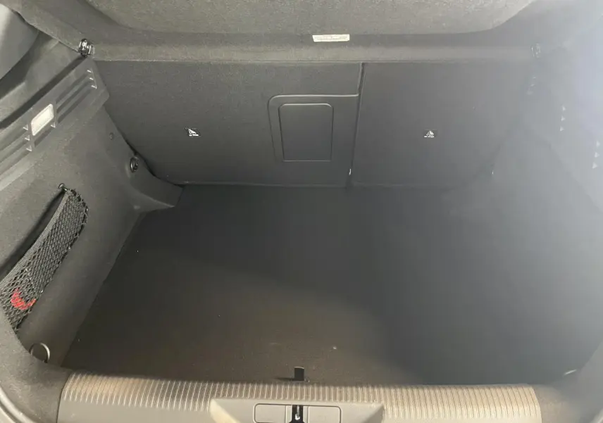 Vue intérieure du coffre spacieux et noir de la Peugeot 308 GT 2026 en gris Selenium, sans chargement visible.