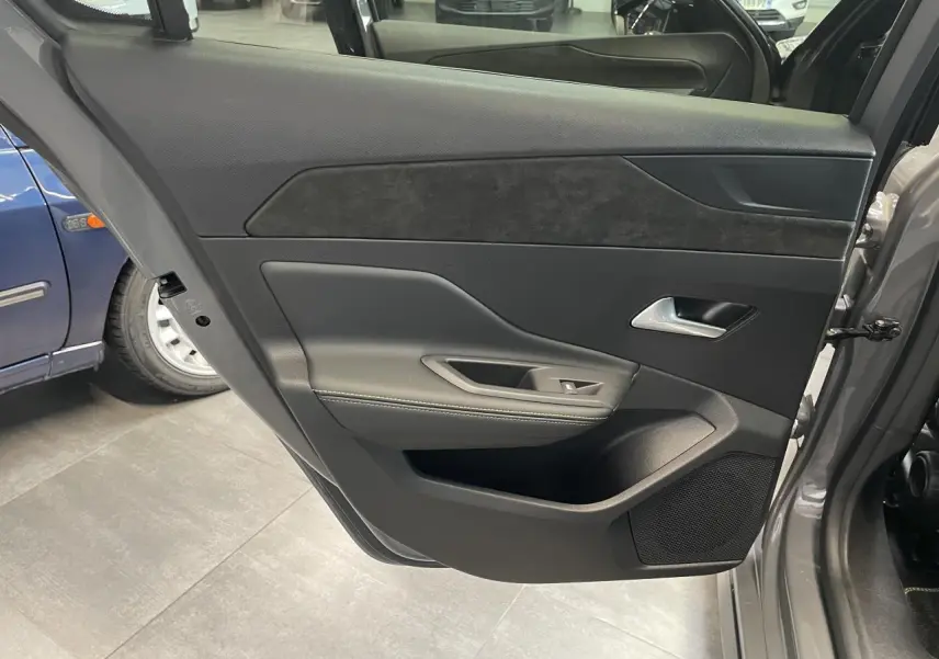 Vue intérieure de la porte arrière droite gris sélénium de la Peugeot 308 GT avec surpiqûres vert Adamite et haut-parleur intégré.