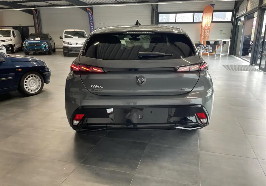 Vue arrière d'une Peugeot 308 GT gris Selenium avec feux arrière LED 3 griffes et jantes alliage en showroom.