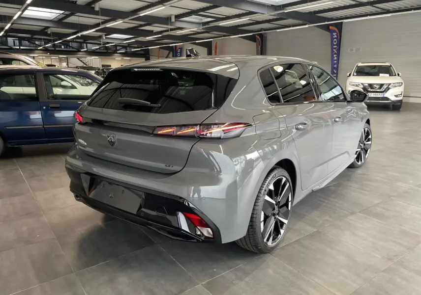Peugeot 308 GT gris Selenium vue 3/4 arrière droit en intérieur, avec jantes alliage bi-tons et feux arrière LED griffés.
