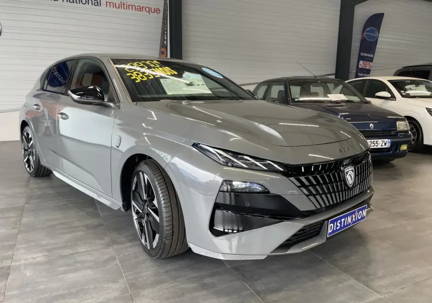 Peugeot 308 gris selenium vue 3/4 avant droit en showroom avec calandre noire et jantes alliage bi-tons.