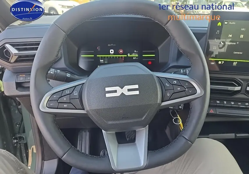 Vue intérieure centrée sur le volant multifonction du Dacia Duster vert kaki avec tableau de bord digital et écran tactile.