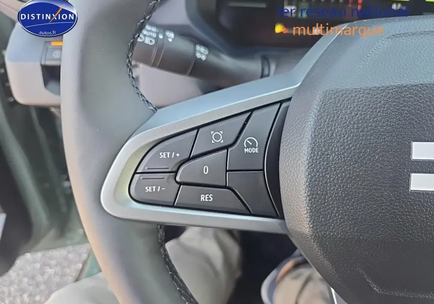 Gros plan sur les commandes multifonctions à gauche du volant du Dacia Duster vert kaki 2025, intérieur conducteur.