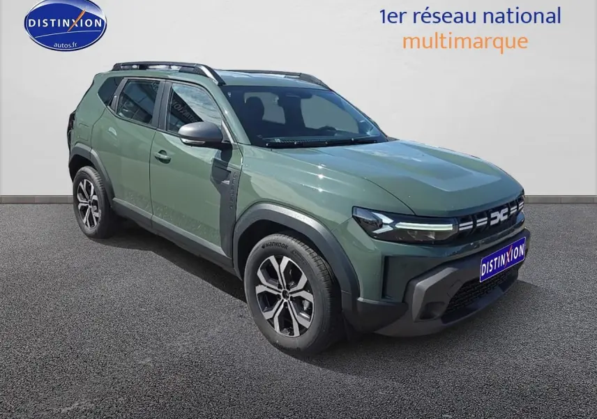 Vue 3/4 avant droit du Dacia Duster 2025 vert kaki avec jantes alu et barres de toit visibles.