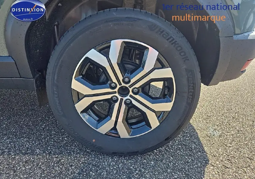 Gros plan sur la roue avant droite du Dacia Duster vert kaki avec jante alu au design moderne.