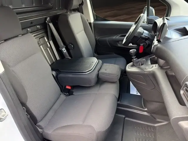 Vue intérieure côté conducteur du Citroën Berlingo blanc 2025, montrant les sièges gris et la console centrale avec levier de vitesses manuel.