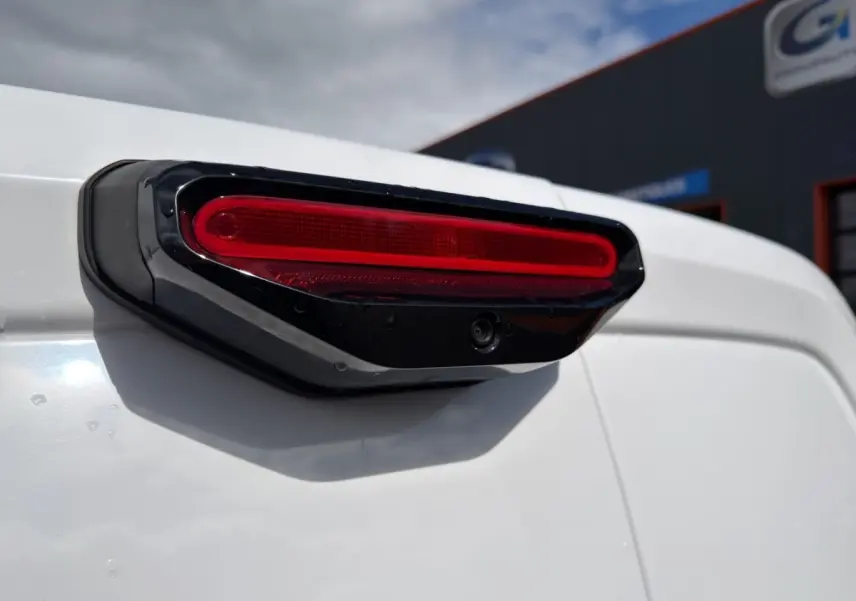 Gros plan sur le feu arrière droit noir et rouge du Citroën Berlingo blanc, vue en légère contre-plongée.