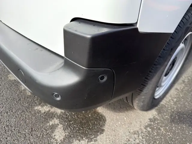 Gros plan sur l'angle arrière droit du pare-chocs noir et la carrosserie blanche du Citroën Berlingo 2025.