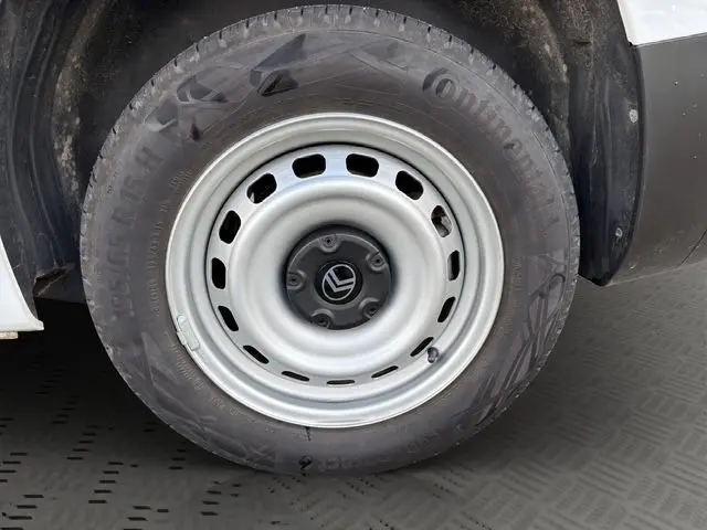 Gros plan sur la roue avant gauche d’un Citroën Berlingo blanc, jante acier avec logo central noir.