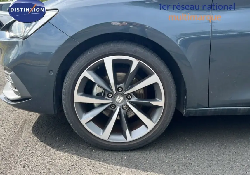 Gros plan sur la roue avant gauche d'une SEAT LEON ST 1.5 eTSI gris magnétique métal avec jante alliage distinctive.
