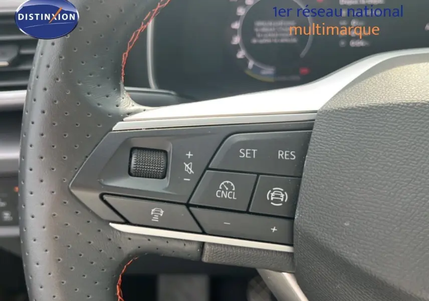 Gros plan sur les commandes au volant du SEAT LEON ST gris magnétique, mettant en valeur les boutons de régulateur de vitesse et assistance conduite.