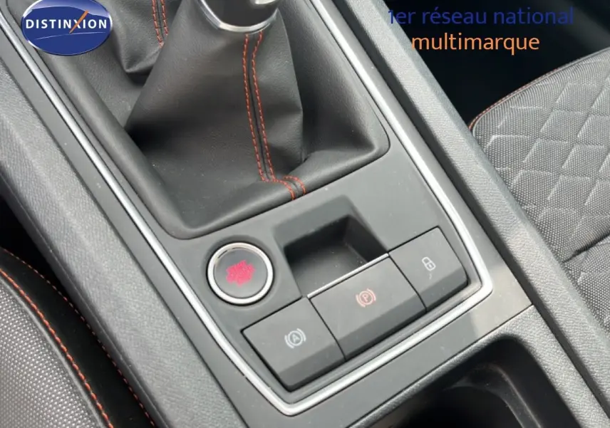 Gros plan sur la console centrale avec levier de vitesse et boutons de commande, intérieur gris noir avec surpiqûres rouges.
