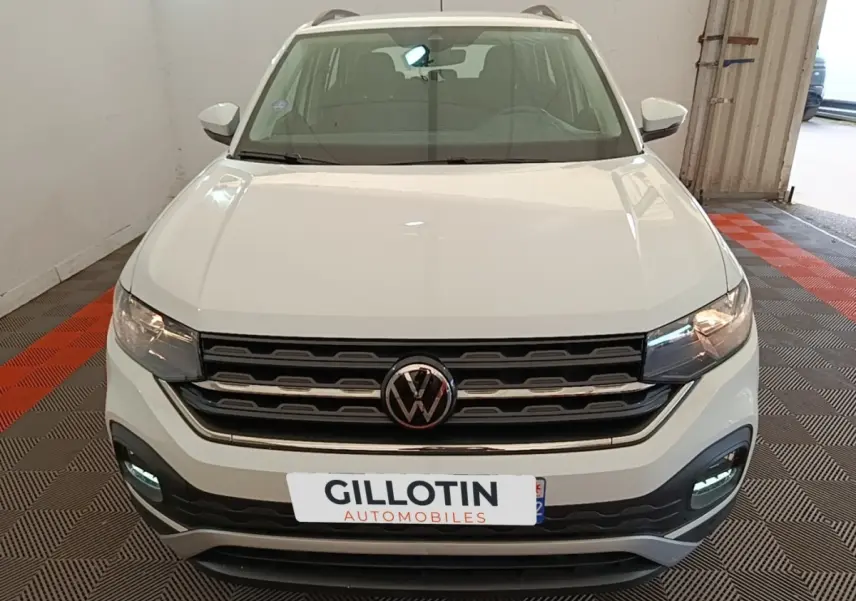 Vue avant d'un Volkswagen T-Cross blanc avec calandre noire et feux diurnes LED allumés en intérieur.