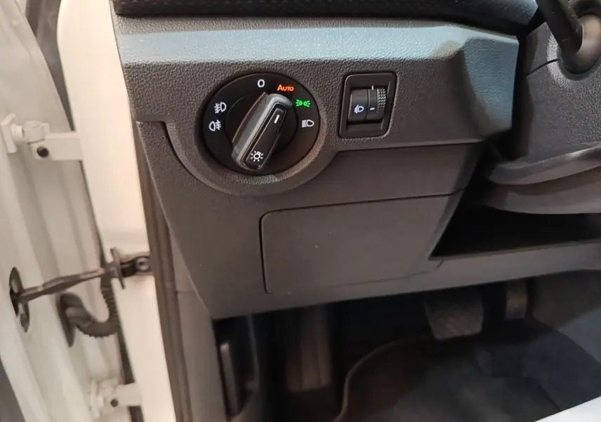 Détail du tableau de bord côté gauche du Volkswagen T-Cross blanc, avec commande d’éclairage et réglage des phares.