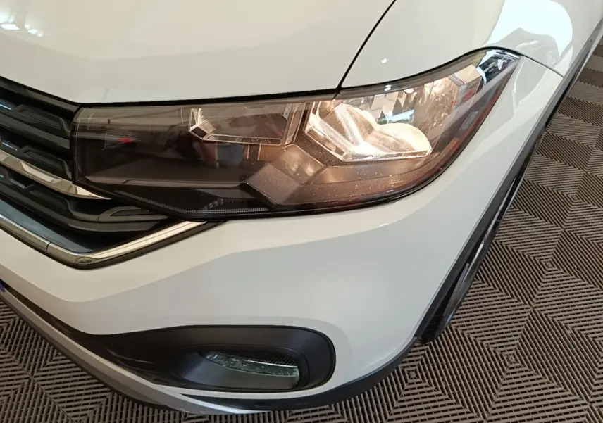 Gros plan sur le phare avant droit blanc du Volkswagen T-Cross 2022 avec antibrouillard et calandre noire.