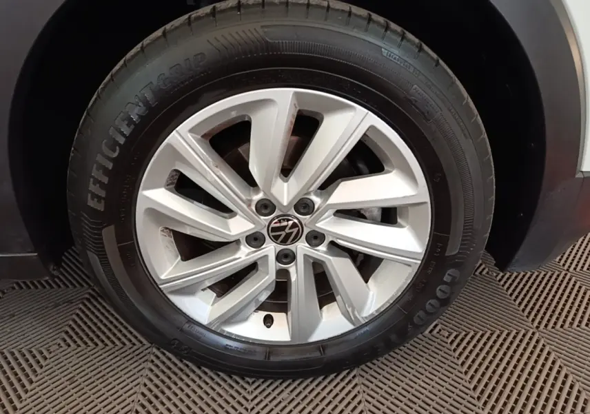 Gros plan sur la jante alliage argentée et le pneu Goodyear d'un Volkswagen T-Cross blanc, côté droit.