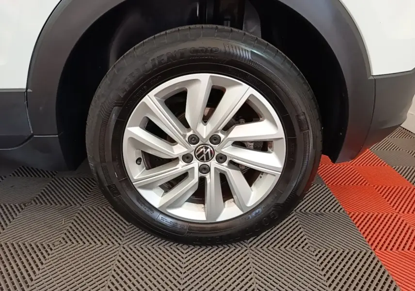 Gros plan sur la roue avant droite d’un Volkswagen T-Cross blanc, jante alliage à dix branches.