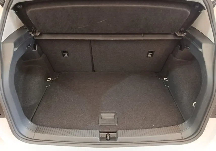 Coffre ouvert du Volkswagen T-Cross blanc, vue plongeante montrant l'espace de chargement vide et la tablette de séparation.