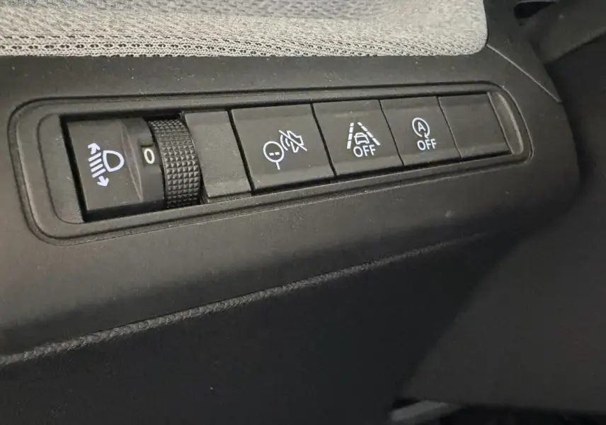 Gros plan sur les commandes de réglage des phares et aides à la conduite dans une Citroën C3 Turbo 100 BVM6 MAX noire.