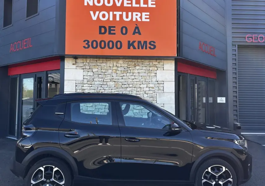 Profil côté gauche d'une Citroën C3 Turbo 100 BVM6 MAX noire, garée devant un bâtiment avec panneau orange.