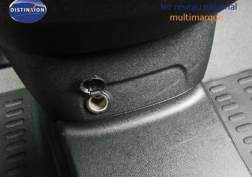 Prise 12V ouverte en gros plan sur la console centrale d’un Citroën Berlingo XL blanc Icy, intérieur noir.