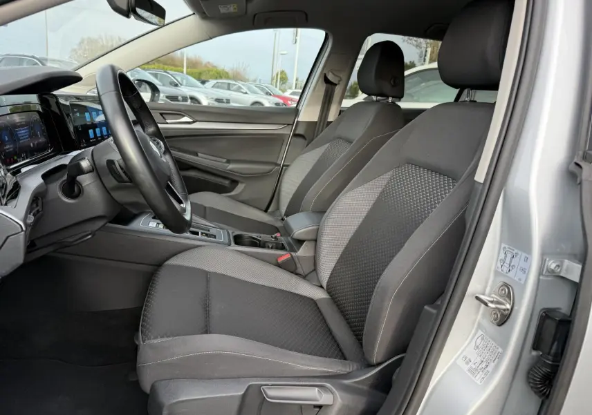 Intérieur avant droit d'une Volkswagen Golf 2022 argent métallisé, sièges tissu gris et tableau de bord moderne.