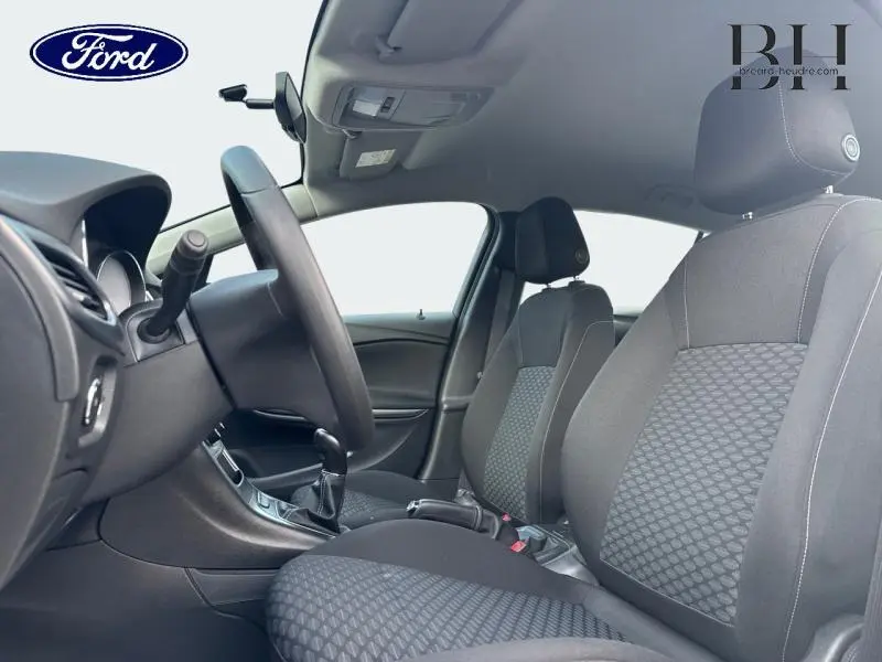 Vue intérieure côté conducteur de l’Opel Astra 1.2 Turbo 2020 avec sièges tissu Talino noir et volant multifonction.