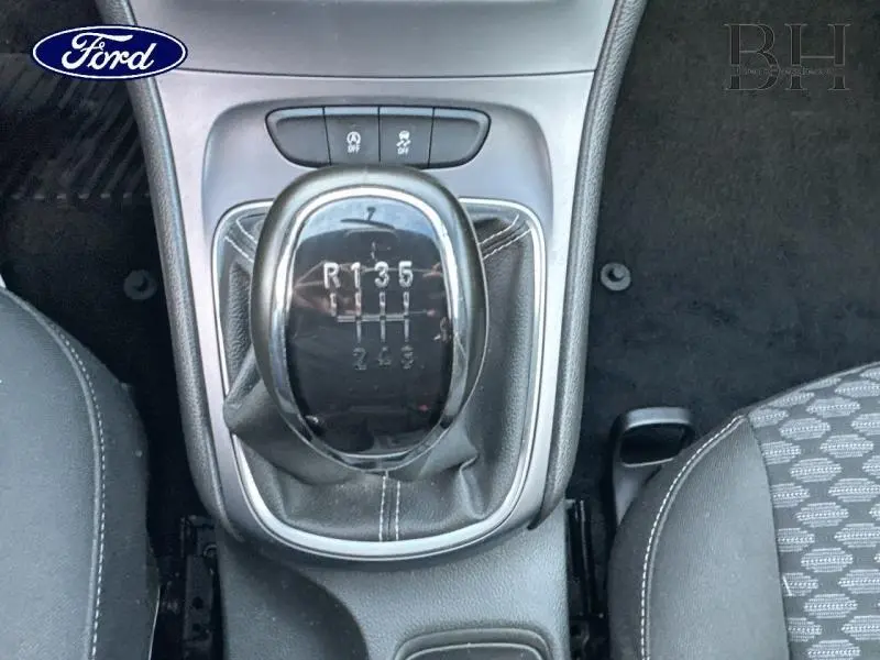 Gros plan sur le levier de vitesses manuel noir avec coutures blanches dans l’habitacle d’une Opel Astra gris minéral.