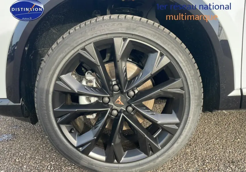 Gros plan sur la jante noire à design géométrique du côté avant droit d’un CUPRA Formentor blanc Nevada.