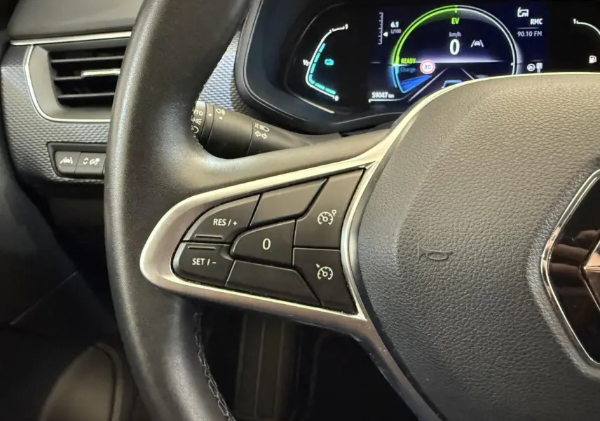 Gros plan sur le volant cuir et alu de la Renault Arkana Business E-TECH 145 avec tableau de bord numérique allumé.