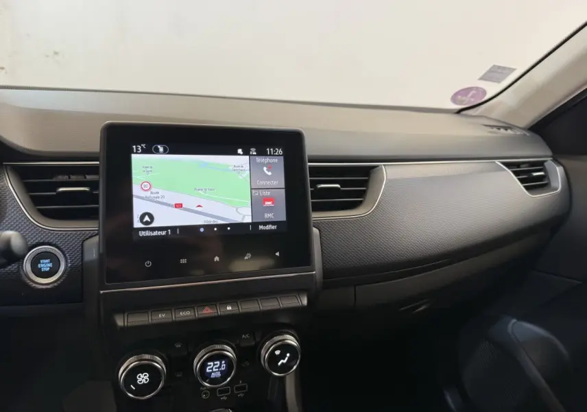 Vue intérieure du tableau de bord de la Renault Arkana Business E-TECH 145 avec écran tactile et commandes climatisation.