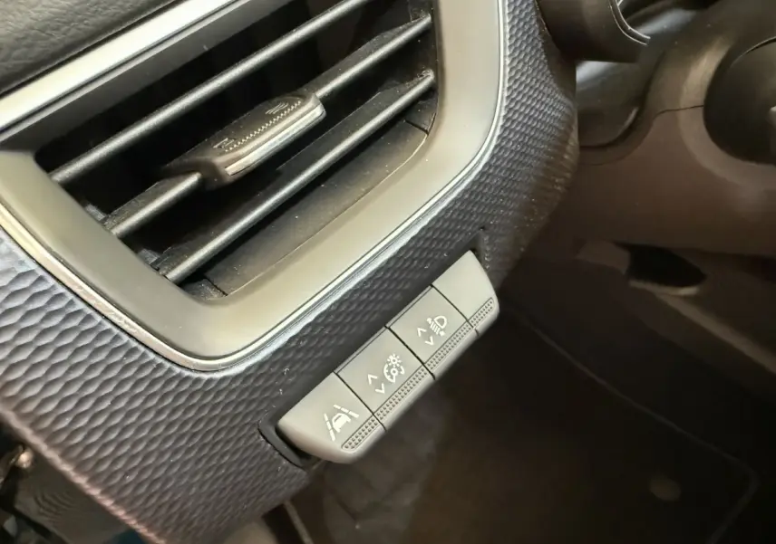 Gros plan sur les commandes d'éclairage et d'assistance au conducteur à gauche du volant dans un Renault Arkana Business E-TECH 145.