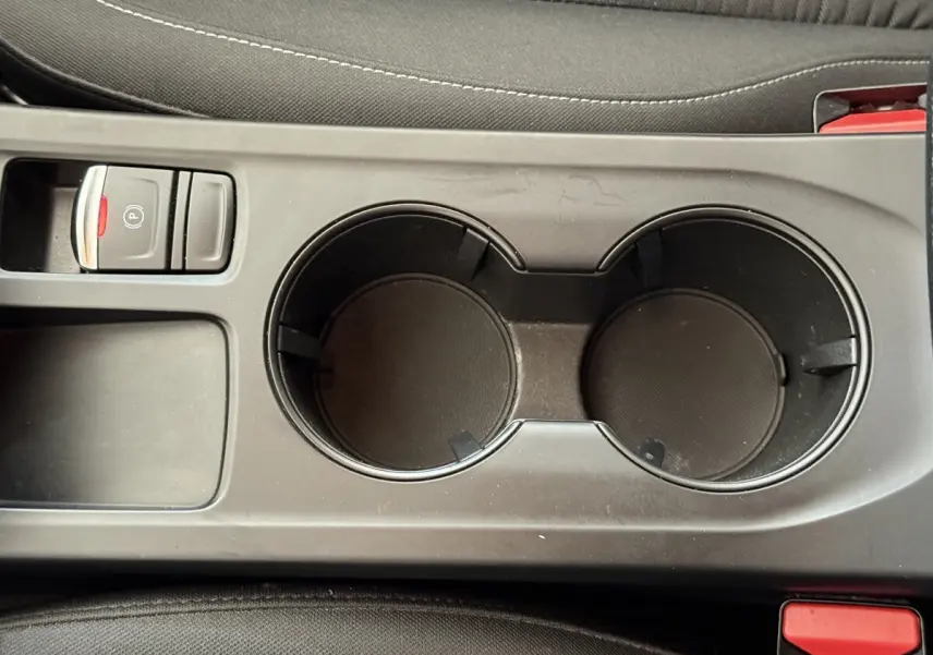 Gros plan sur la console centrale noire avec porte-gobelets et frein à main électrique de la Renault Arkana Business E-TECH 145.