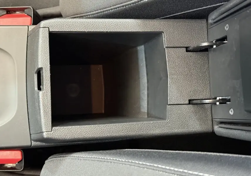 Vue en plongée sur le rangement central noir de l’habitacle du Renault Arkana Business E-TECH 145 bleu de 2022.