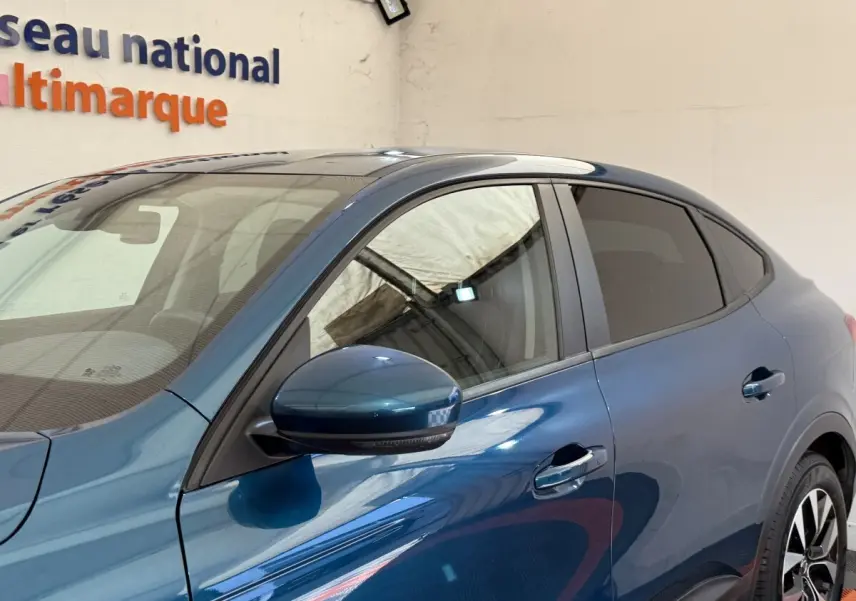 Vue de côté gauche du Renault Arkana Business E-TECH 145 bleu, mettant en valeur la porte et le rétroviseur latéral assorti.