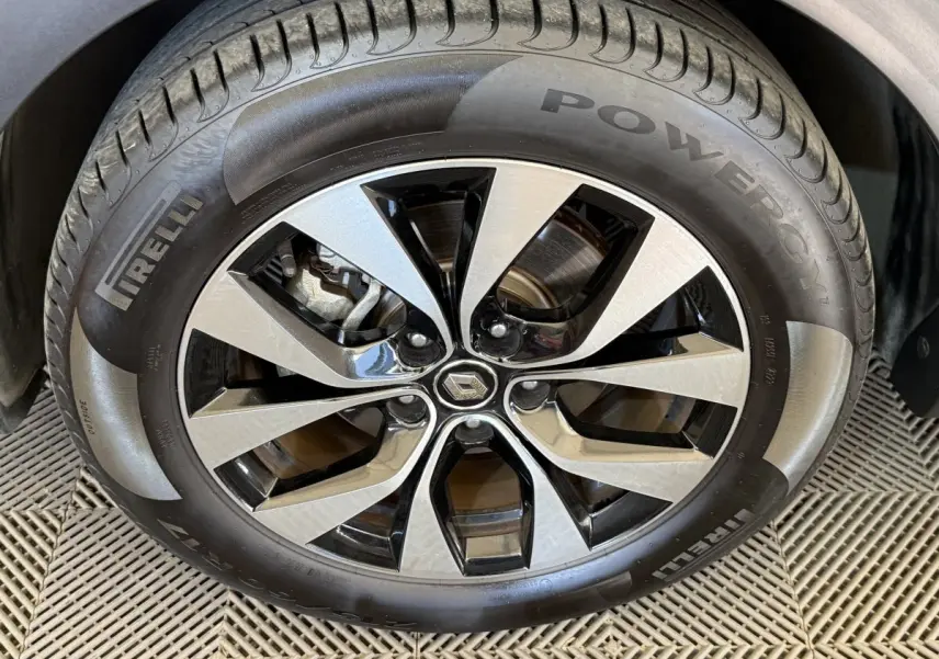 Gros plan sur la jante alu bicolore et le pneu Pirelli d'une Renault Arkana Business E-TECH bleu, vue côté roue avant.
