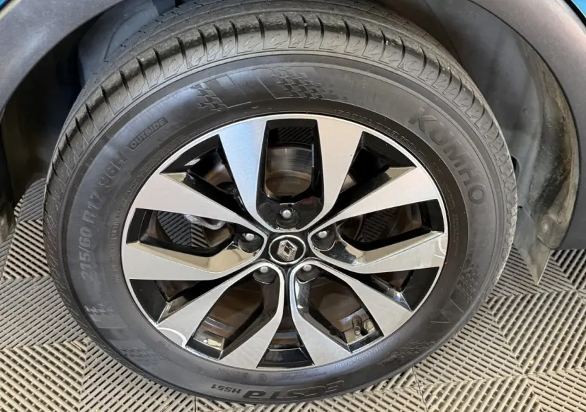 Gros plan sur la roue avant droite d’un Renault Arkana bleu, avec jante alliage bicolore et pneu Kumho.