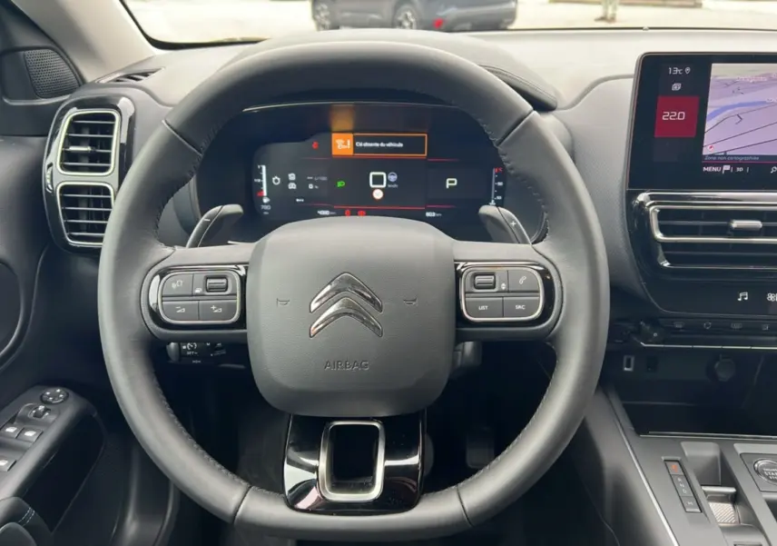 Vue intérieure centrée sur le volant cuir multifonctions du Citroën C5 Aircross Hybrid noir avec tableau de bord digital.