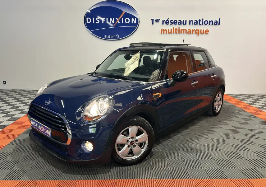 Vue 3/4 avant droite d'une MINI 5 portes Cooper D bleu avec toit ouvrant dans un showroom lumineux.
