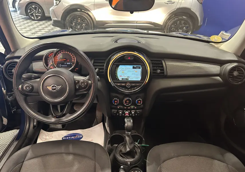 Vue intérieure avant de la MINI 5P Cooper D bleu, avec tableau de bord et écran GPS central lumineux.