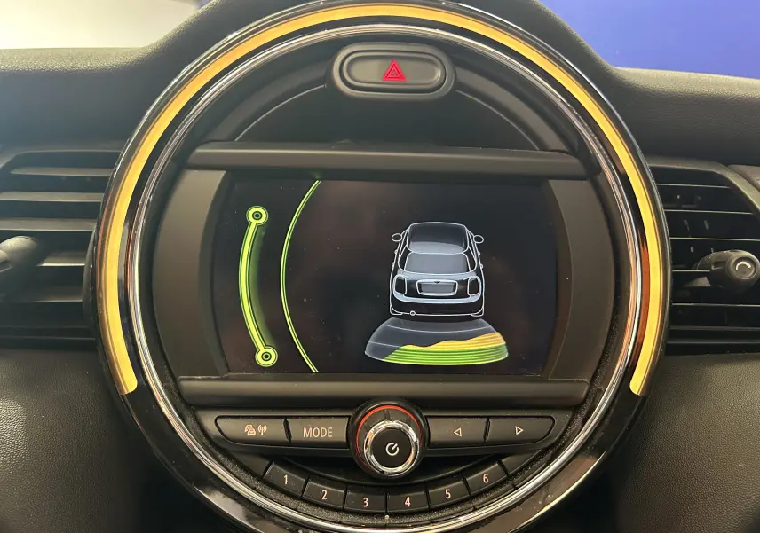 Affichage central du tableau de bord de la MINI 5P Cooper D 2015, montrant l'alerte de proximité arrière avec cercle lumineux jaune.