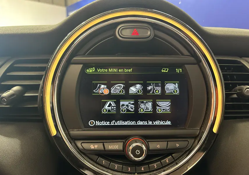 Vue rapprochée de l’écran central rond de la MINI 5P Cooper D 2015 avec interface digitale et éclairage orange autour.