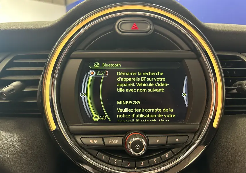 Vue rapprochée de l’écran central rond du tableau de bord d’une MINI 5P bleu, affichant le menu Bluetooth.